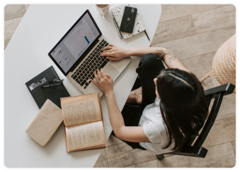 Μια κοπέλα κάθεται στο γραφείο και δουλεύει στο λάπτοπ.